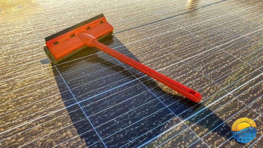 a broom laying on top of a dirty solar panel